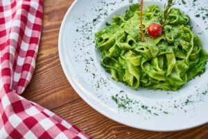 Pasta in a fresh green sauce on plate garnished with herbs. 