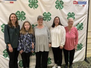 Women in front of 4-H backdrop at banquet